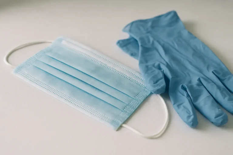 Masque et gants de protection sur une surface propre, utilisés pour la désinfection après décès.
